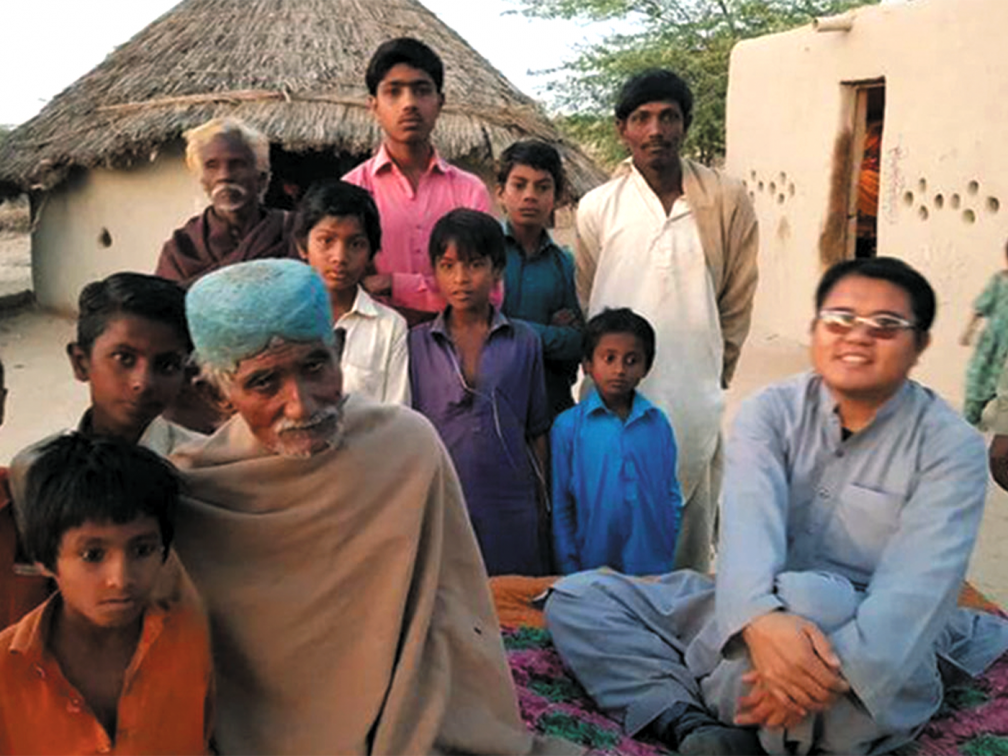 family faces looking into the camera in front of a pakistani home