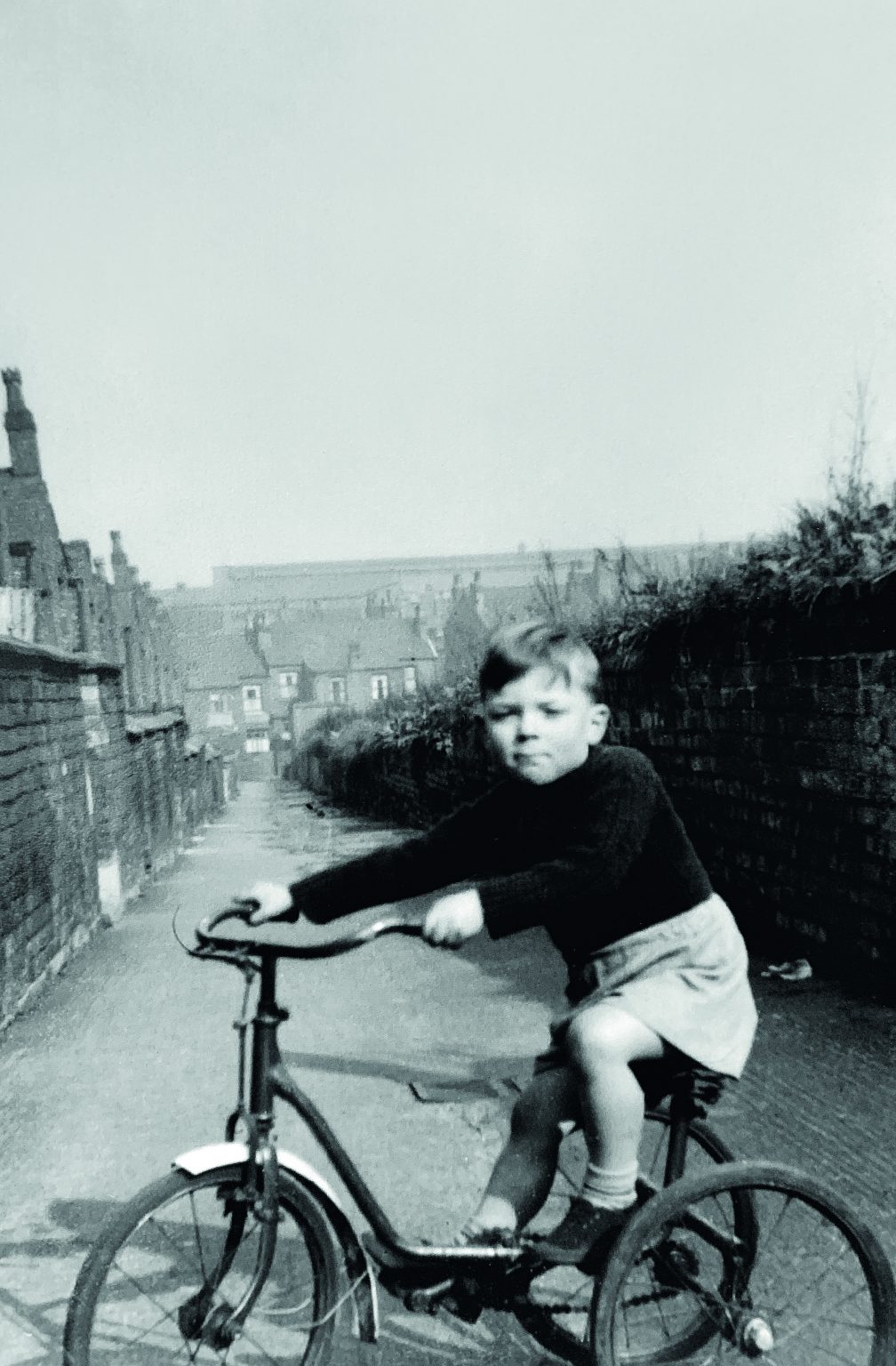 A black and white photograph of a young John Boles on a bike