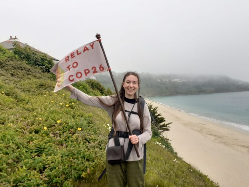 Molly Clark holds a flag with a beach and the sea in the background