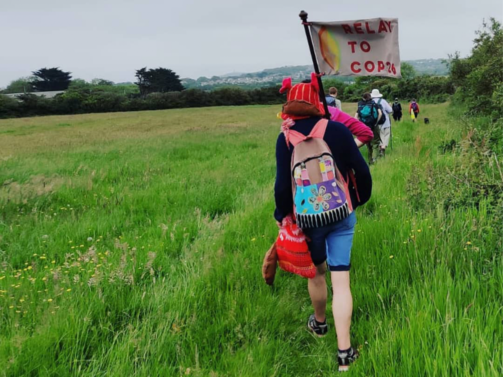 YCCN walkers cross a field holding a banner