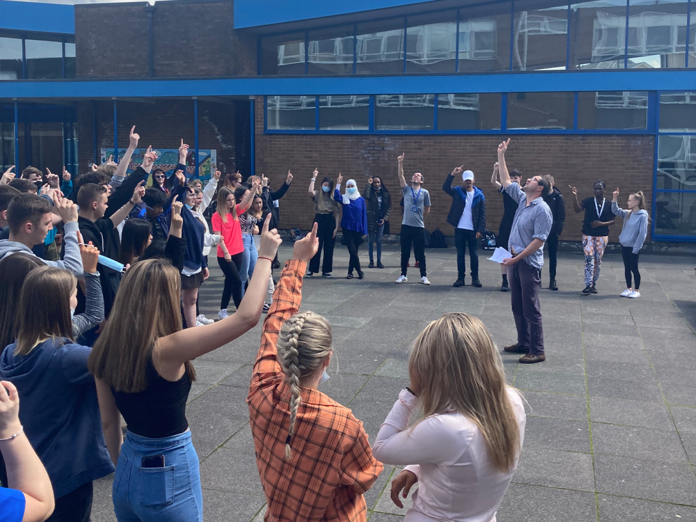 James and students point to the sky with their fingers