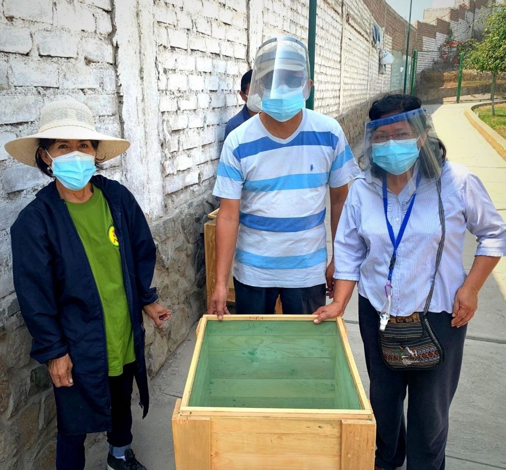 people surround a veg box.