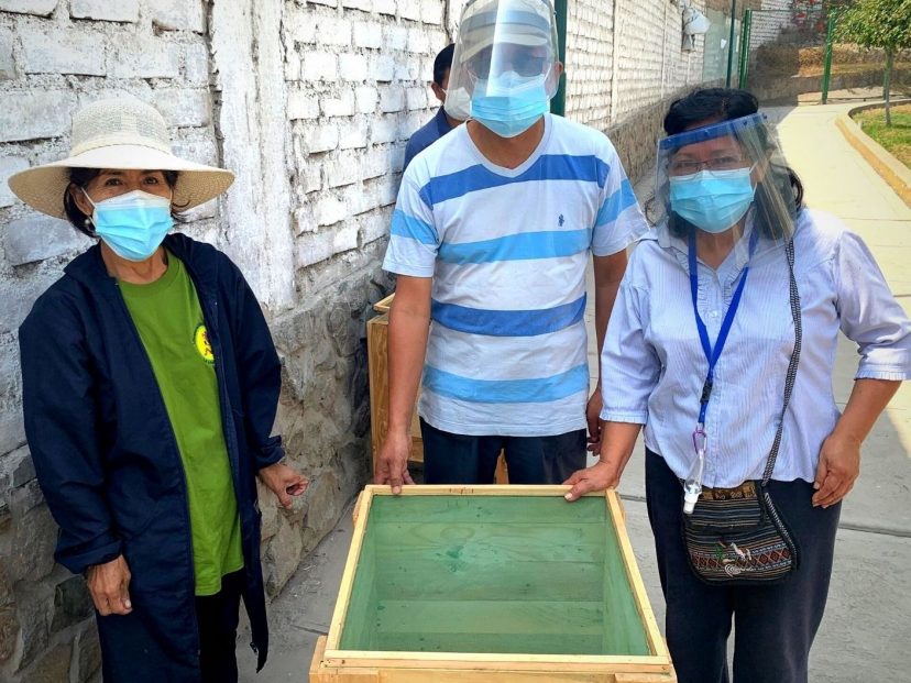 people surround a veg box.