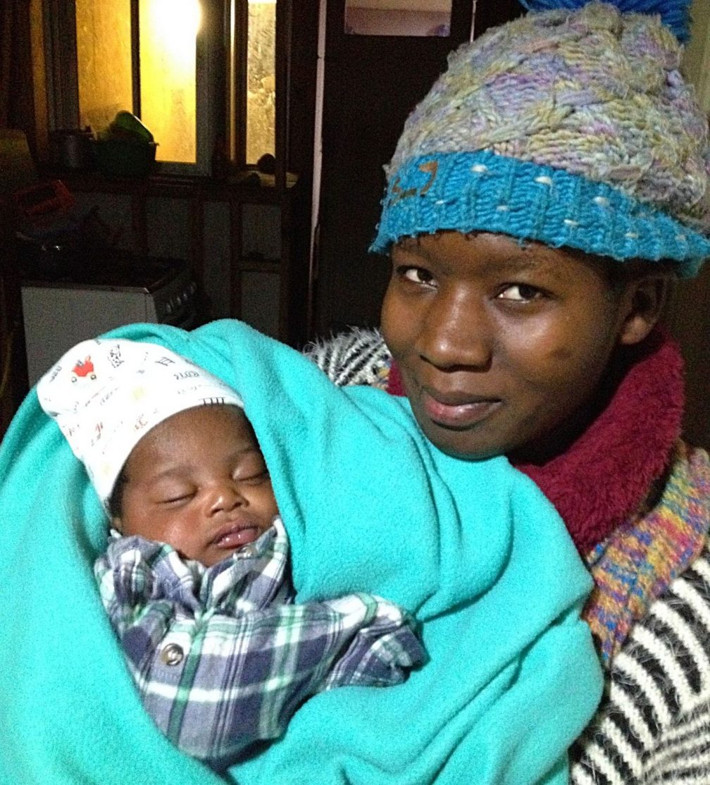 migrant woman holding a small baby wrapped in blanket