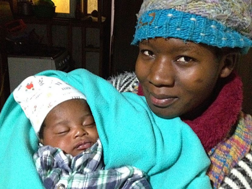 migrant woman holding a small baby wrapped in blanket