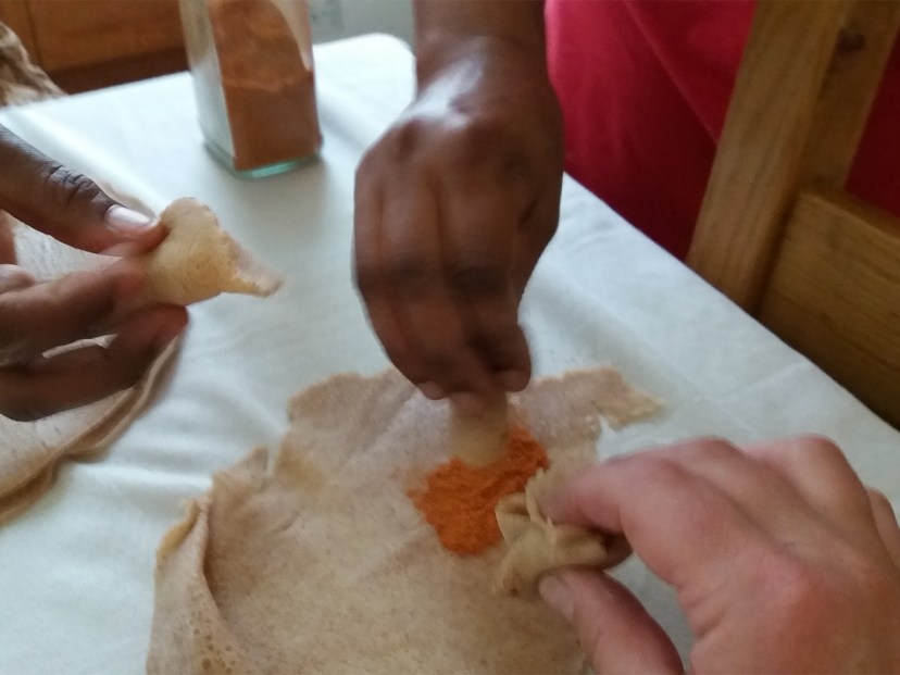 women's hands dipping bread into a dip