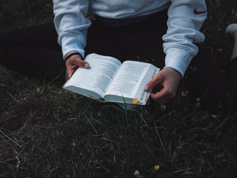 person in white jumper with a bible open