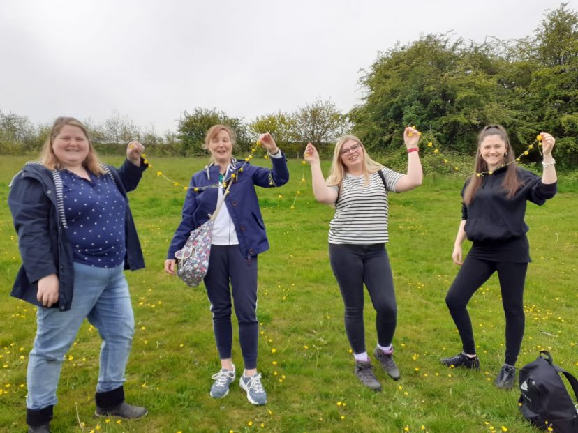 teachers outside in a field hold up bunting
