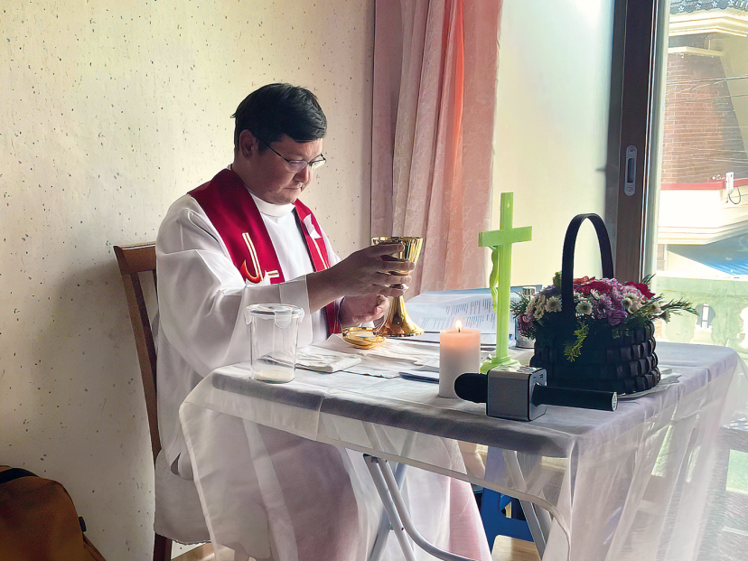 priest in front of a homemade altar in a house