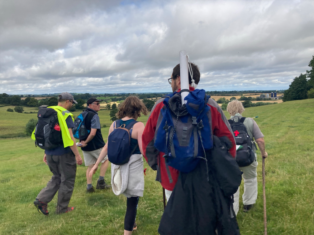 backs of walkers through grassy fields