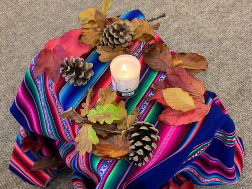 colourful tablecloth with autumn leaves and a candle burning.