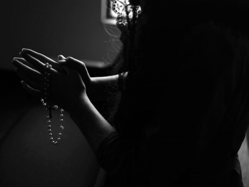 female holding rosary and praying