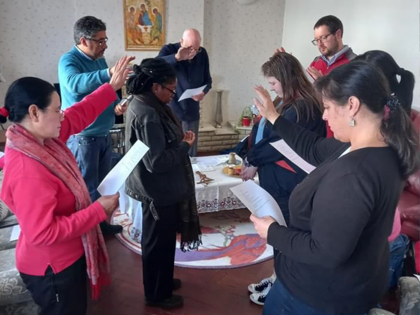 group of people have their hands over two females praying