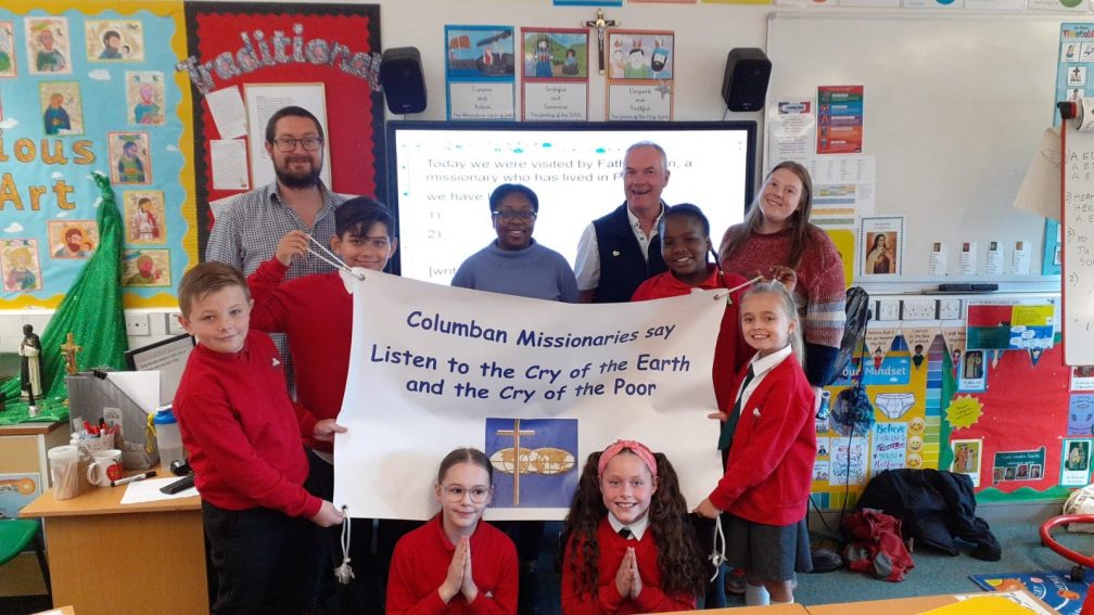 students and adults hold a Columban banner