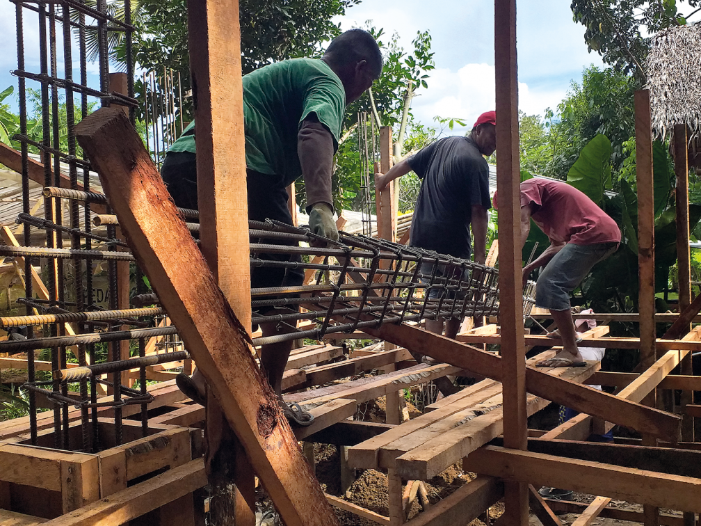 men carry timbers for building work