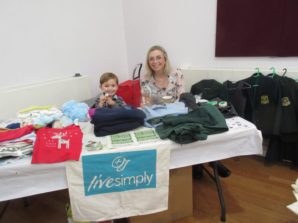 lady and young boy with piles of school uniforms
