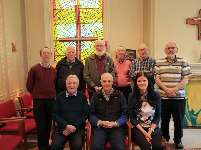 Team members look at the photo against a brightly coloured stained glass window