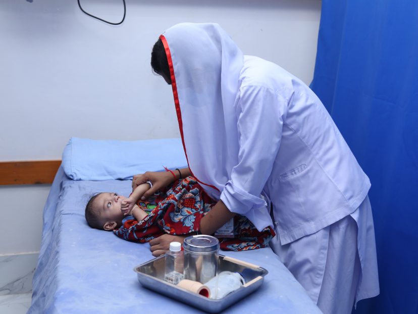 female nurse bent over a small and ill infant