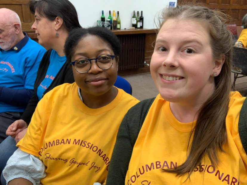 two volunteers in yellow tops smile to the camera