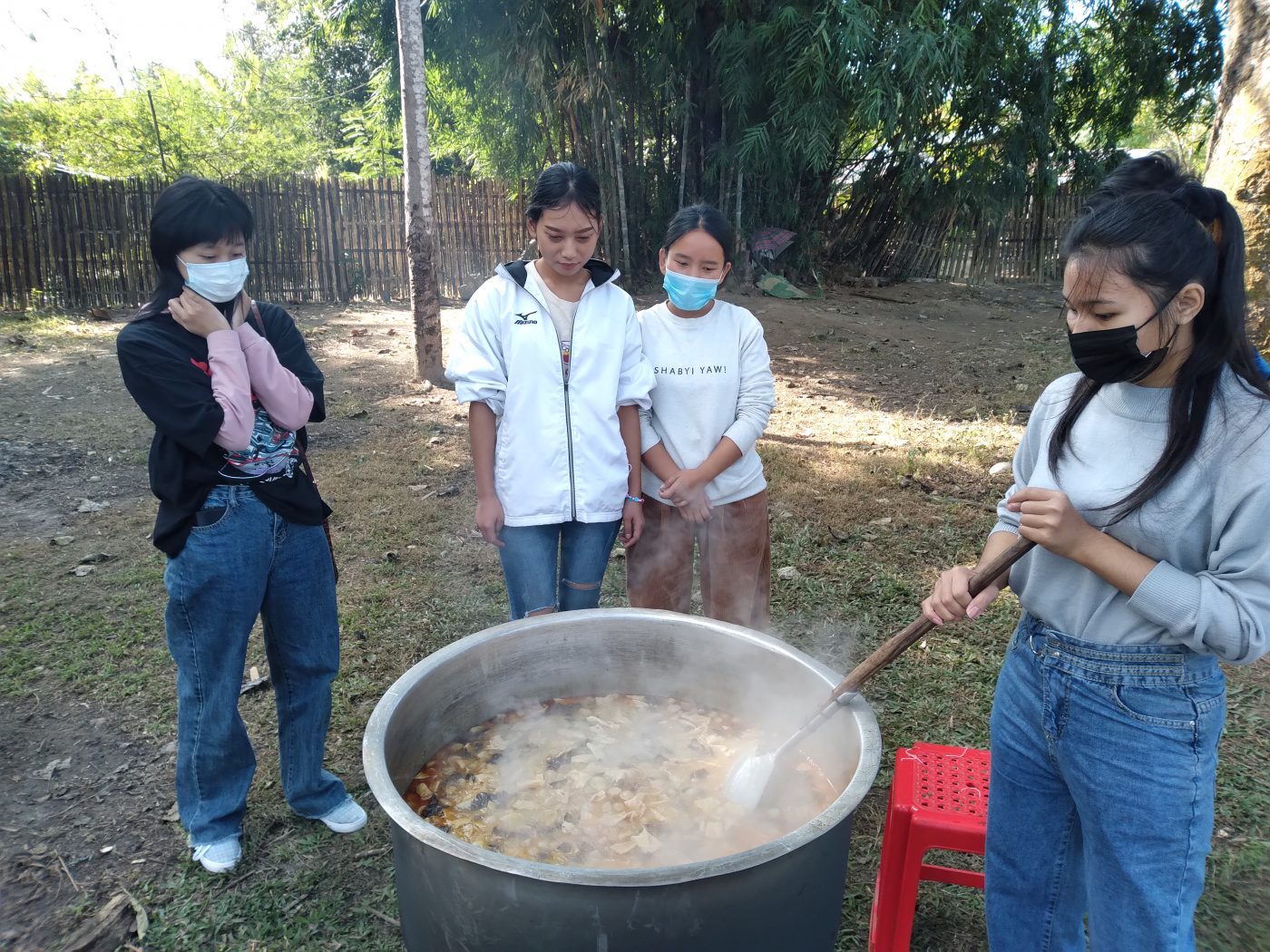 students crowd around a big soup pot