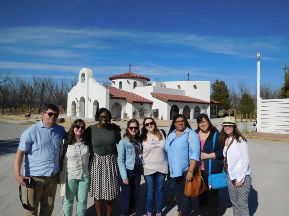 group pose for photo against a blue sky