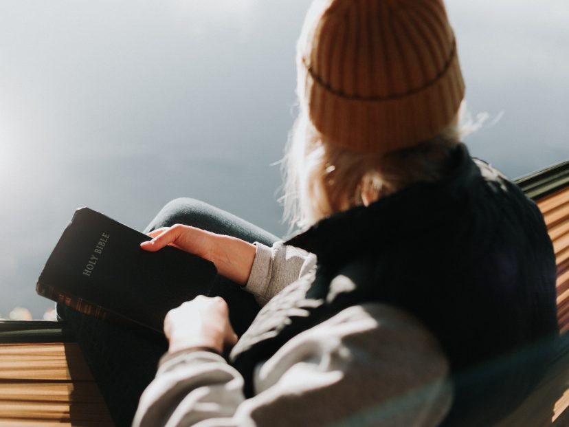 individual holds bible and looks out over water
