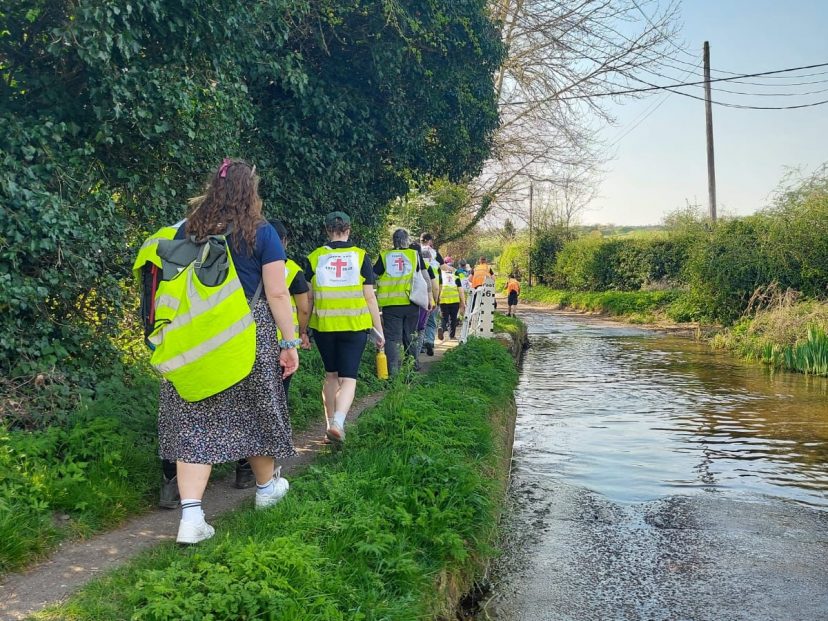 people in high visibility jackets walk along a canal path