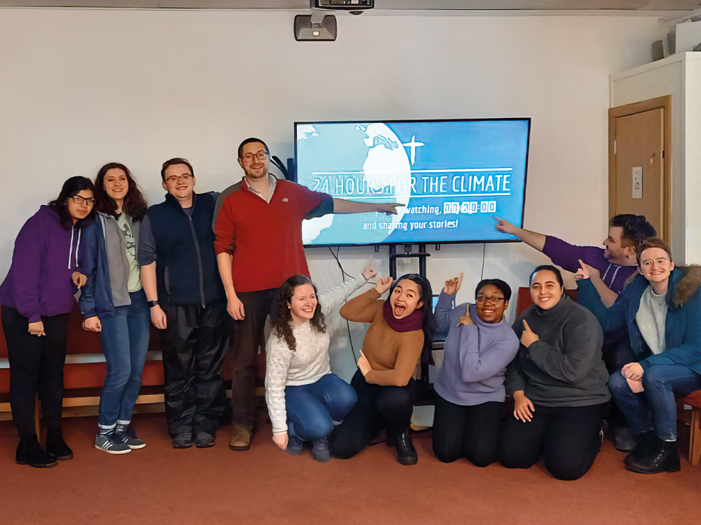 team gather around a TV screen with 24 hours for the climate