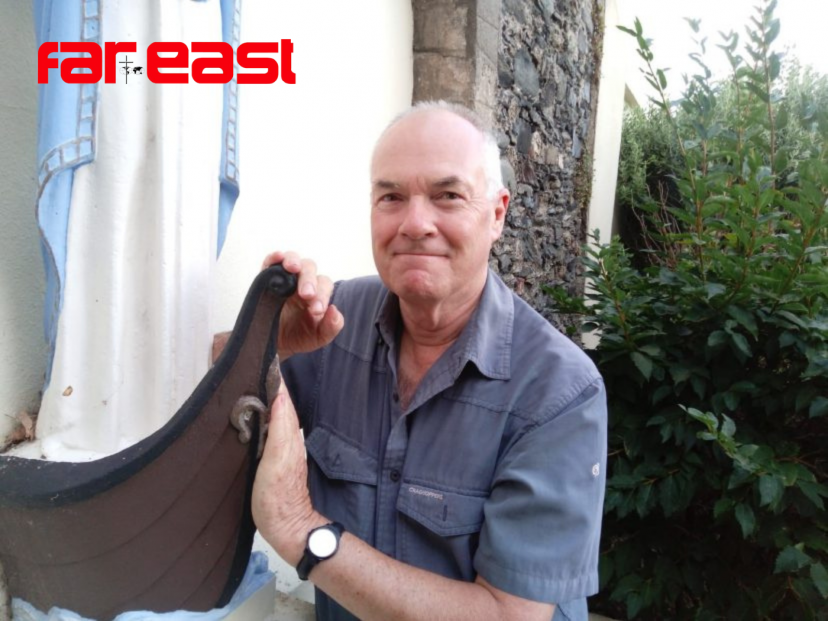 Fr. John Boles beside the 'oar-less coracle', symbol of St. Maughold, outside the church in Ramsey