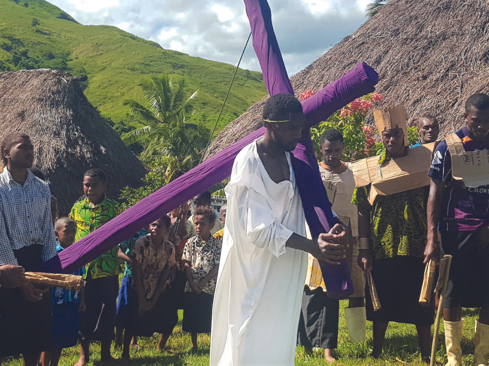 young parishioner carries the cross