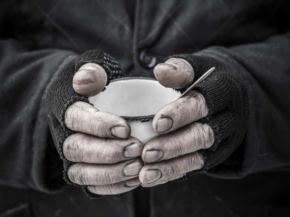Homeless person with dirty fingernails holds a mug