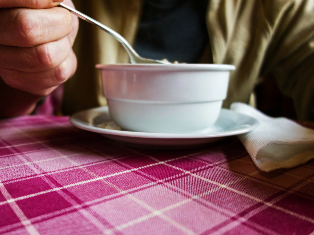man eats soup at a table with pink tablecloth