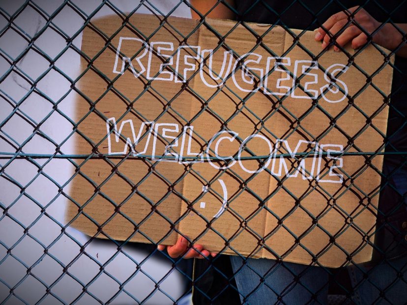 refugees welcome sign behind a wire fence