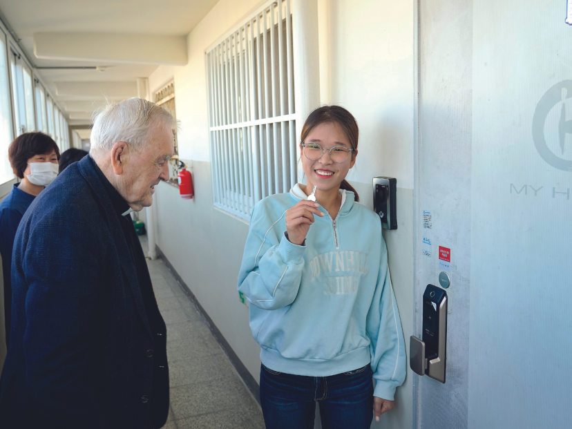 Kim Yoon Cheong holding the key to her first home, watched by Columban missionary, Fr. Noel O’Neill