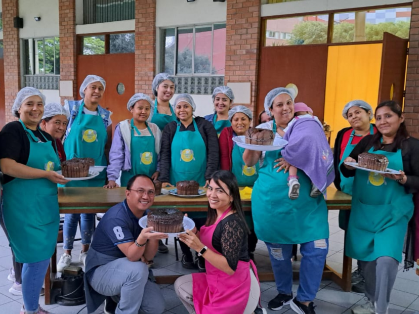Columban Fr. Erl Dylan Tabaco and Columban Co-worker Marisol Rojas (kneeling) with Venezuelan migrants and Peruvian internal migrants during the pastry workshop held at the Columban Centre for Missionary Studies