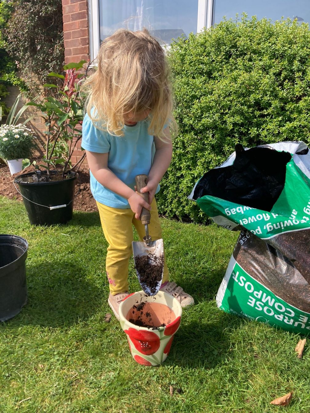 One of Emma's daughters helping to plant seeds and plants in the family's garden