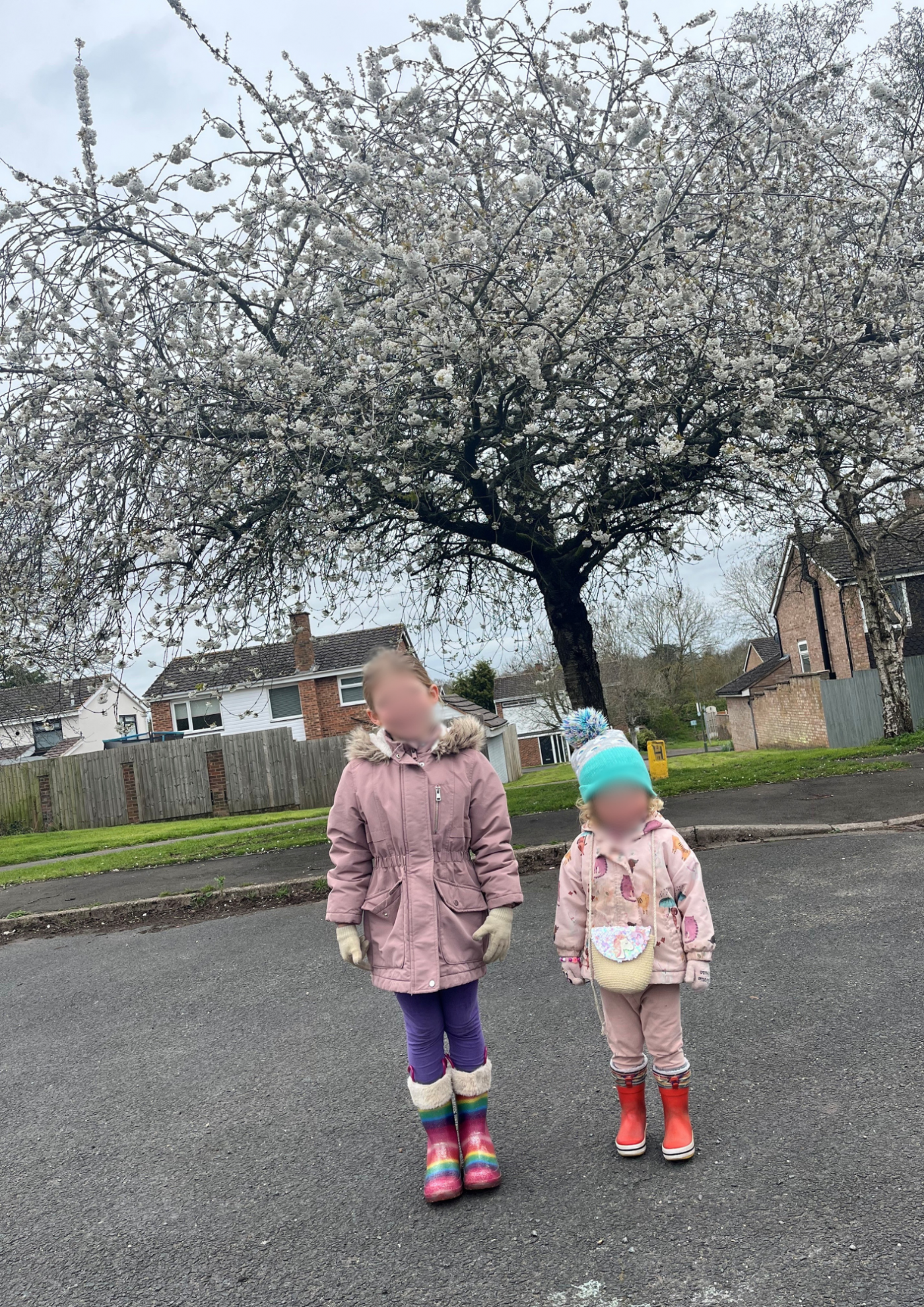 Emma's two daughters in front of a large cherry tree outside their home which during Spring is adorned with white blossom