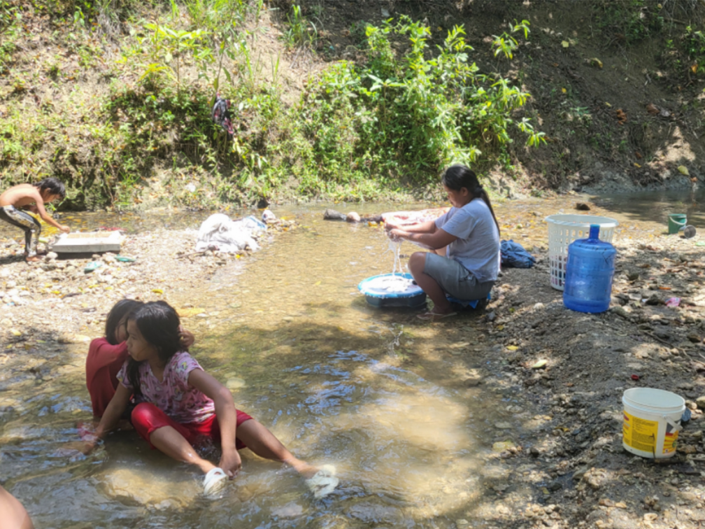 A woman uses rainwater to clean her family's clothing