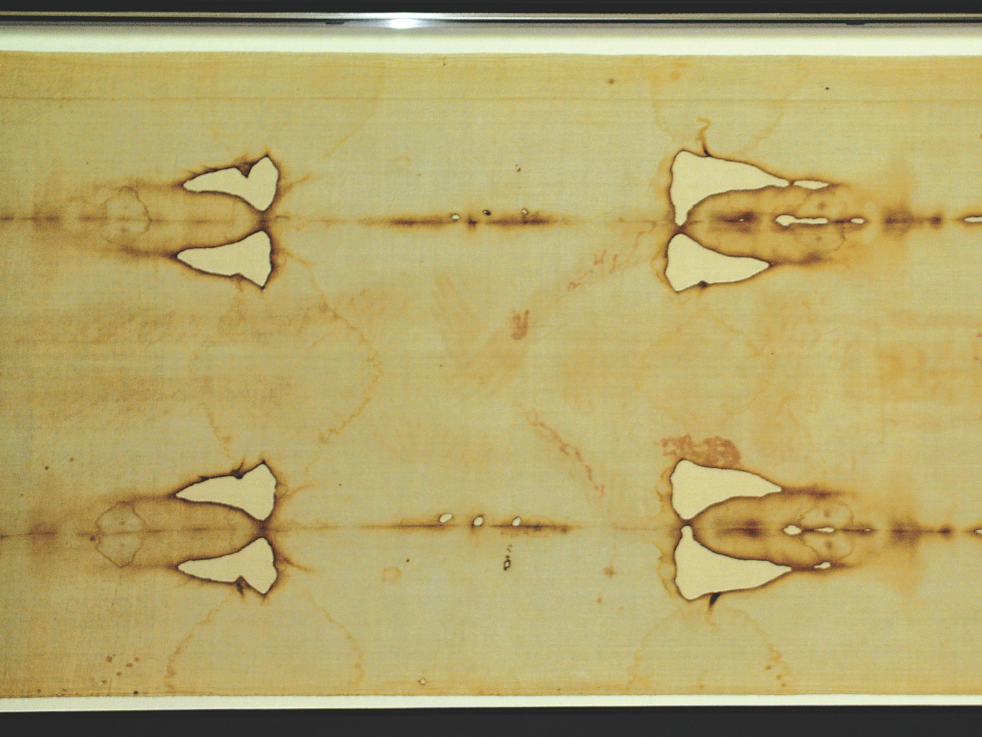 The shroud is rectangular, measuring approximately 4.4 by 1.1 metres (14 ft 5 in × 3 ft 7 in). The cloth is woven in a three-to-one herringbone twill composed of flax fibrils. Its most distinctive characteristic is the faint, brownish image of a front and back view of a naked man with his hands folded across his groin. The shroud was damaged in a fire in 1532 in the chapel in Chambéry, France. There are some burn holes and scorched areas down both sides of the linen, caused by the fire that burned through it in places while it was folded. Fourteen large triangular patches and eight smaller ones were sewn onto the cloth by Poor Clare nuns to repair the damage