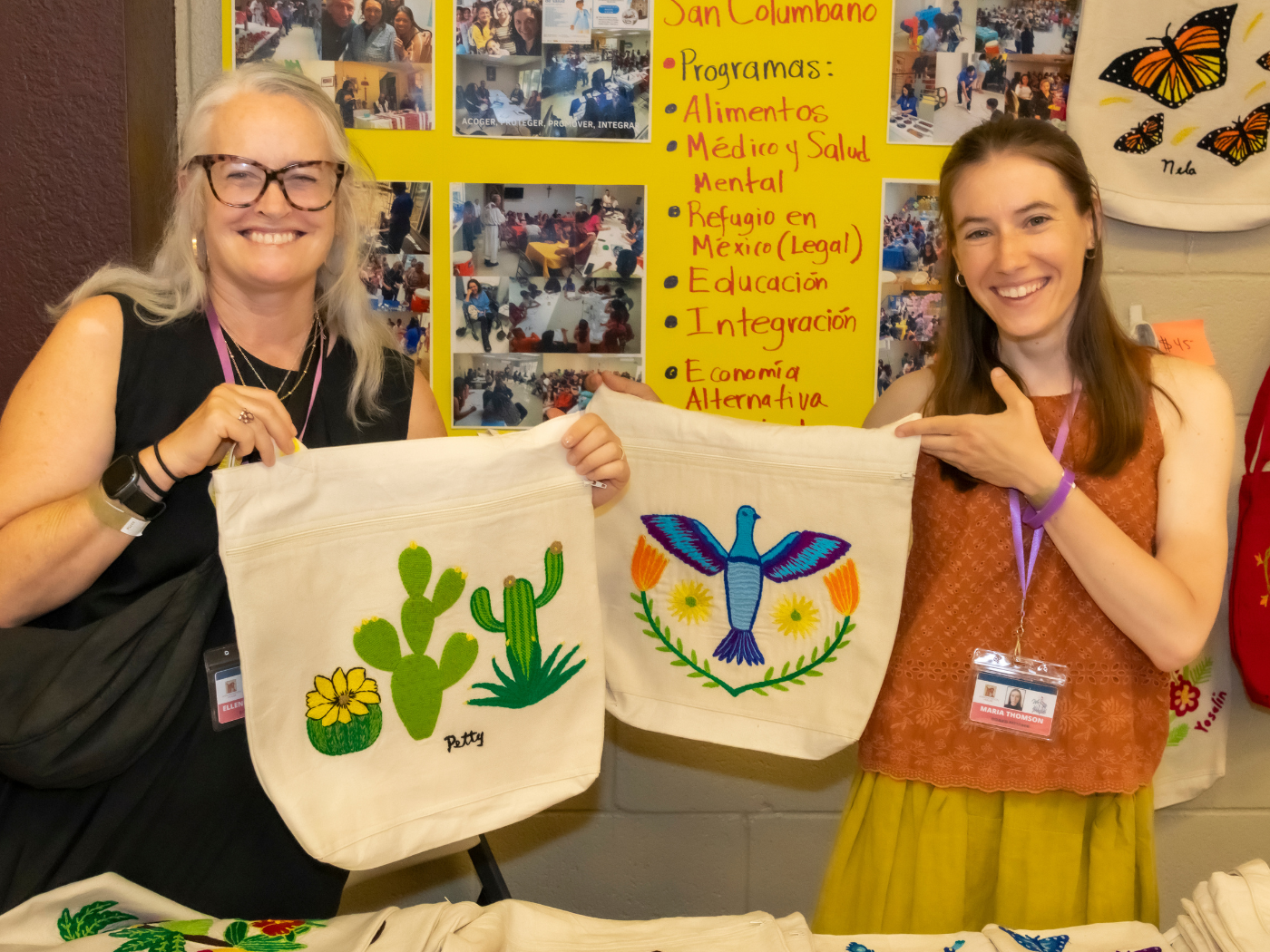 Two of Annunciation House’s Board Members at a display stand for work from the Columban embroidery project for migrants