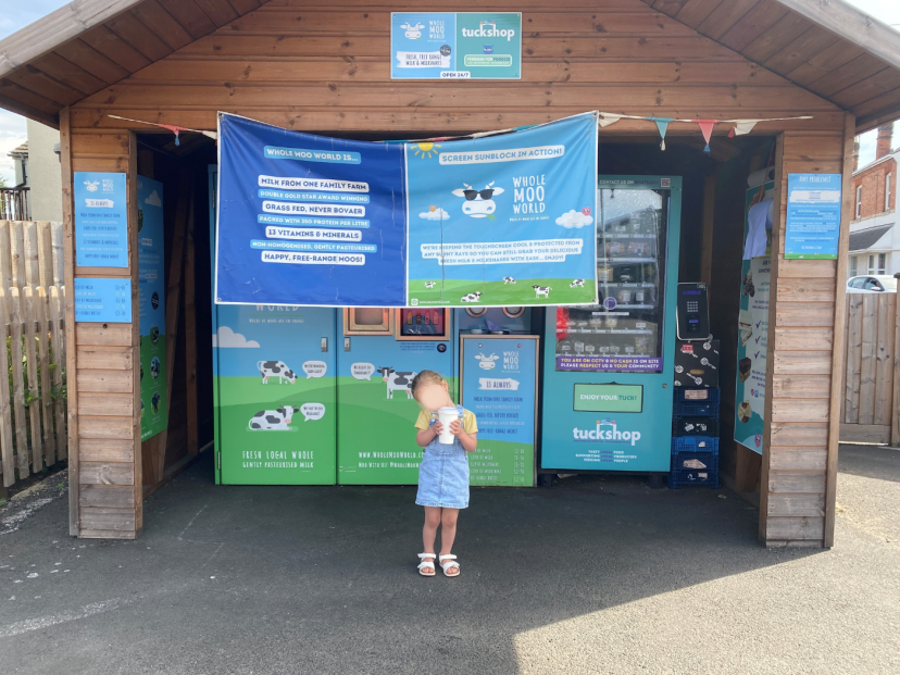 Emma's daughter outside the Whole Moo World fresh milk vending machine near er home in Worcestershire