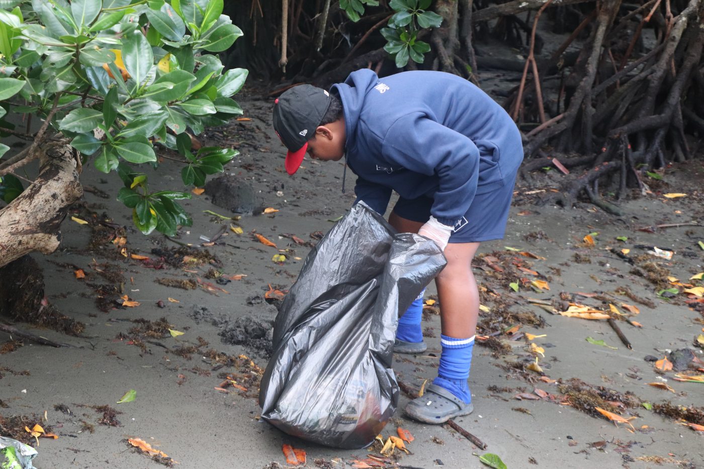 A participant picks up plastic waste among other rubbish from Suva's foreshore