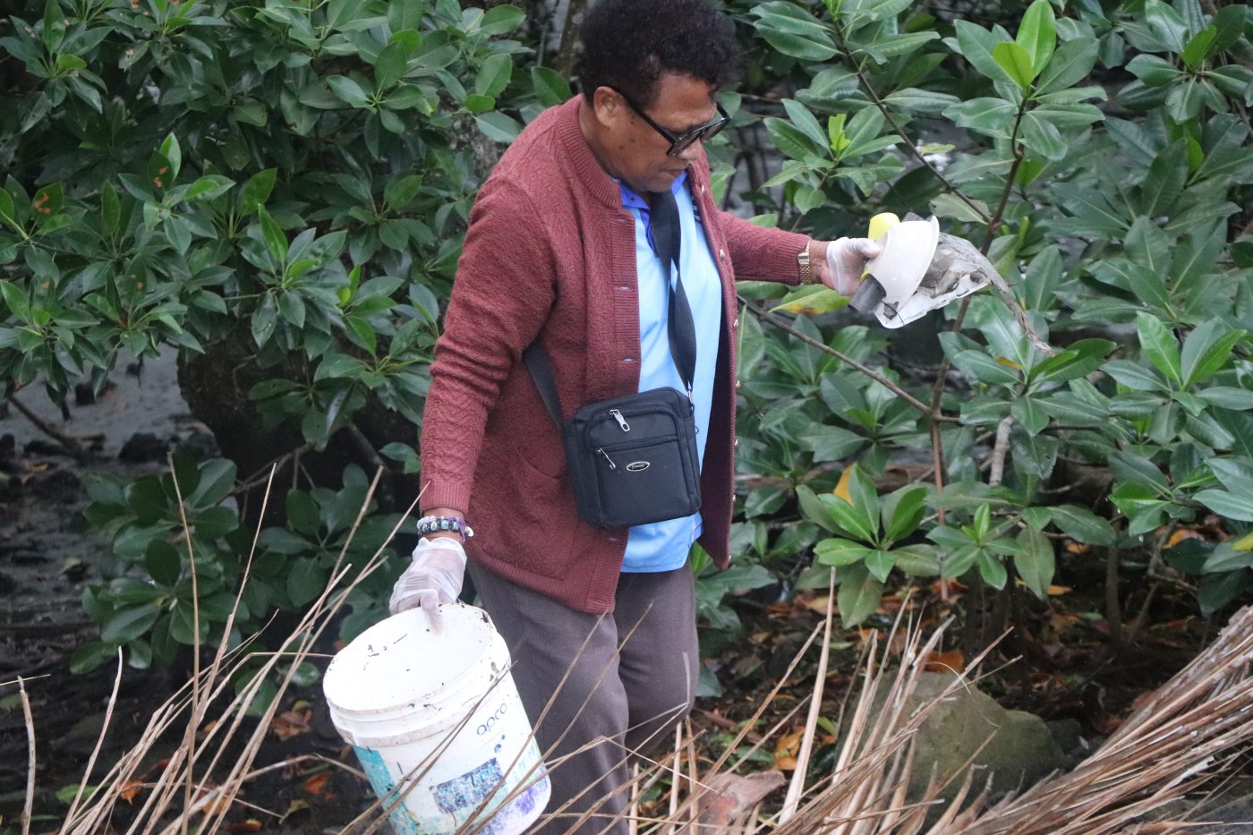 A participant of the beach clean up collects plastic rubbish