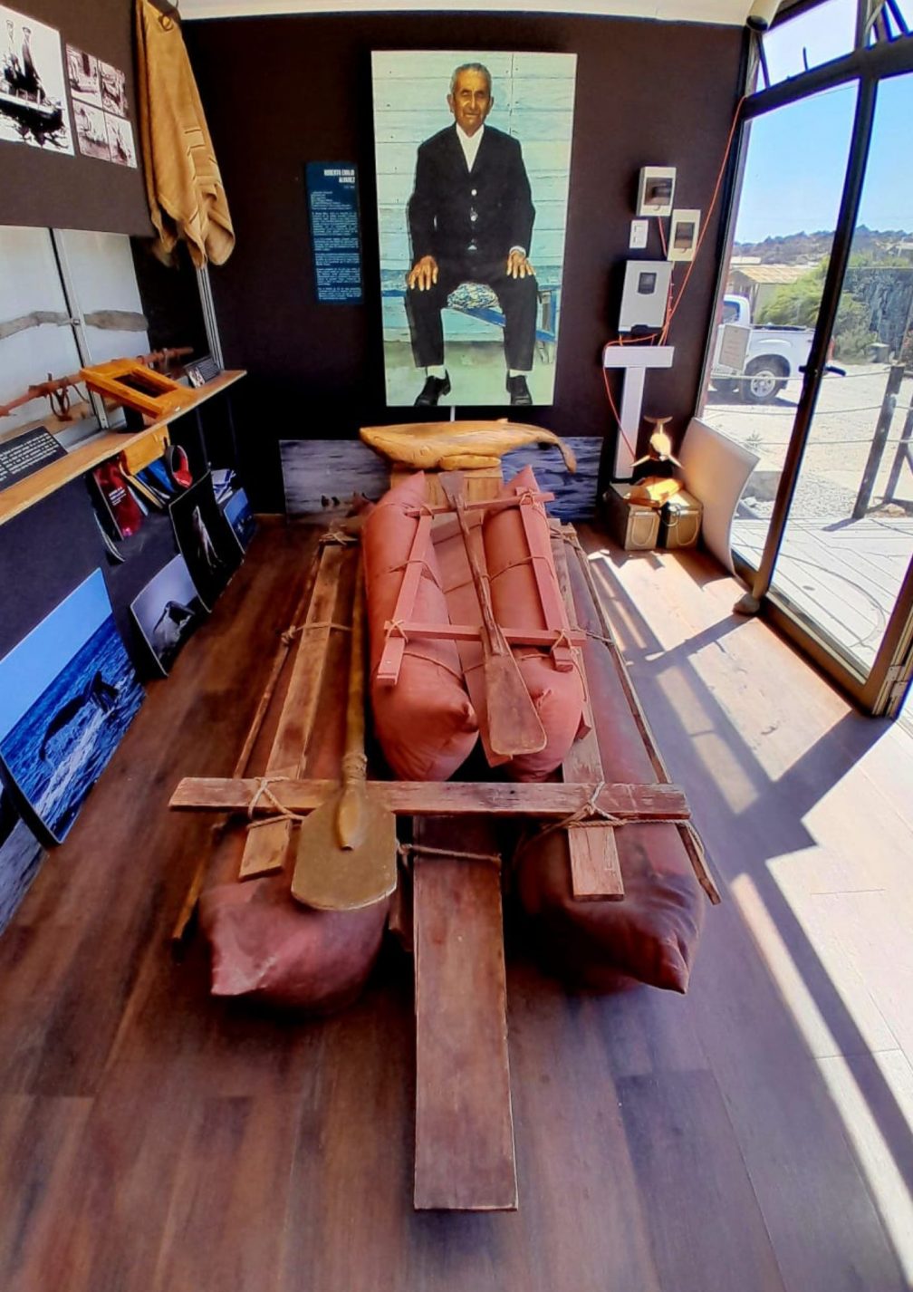 A replica of the boat made from sea lion hide with an image of Chango Roberto Alvarez in the background at the Museugrafico in Caleta Chañaral de Aceituno, Chile