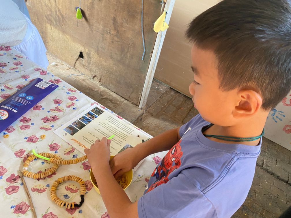 A young participant engages in a craft activity; makingn bird feeders using cereal