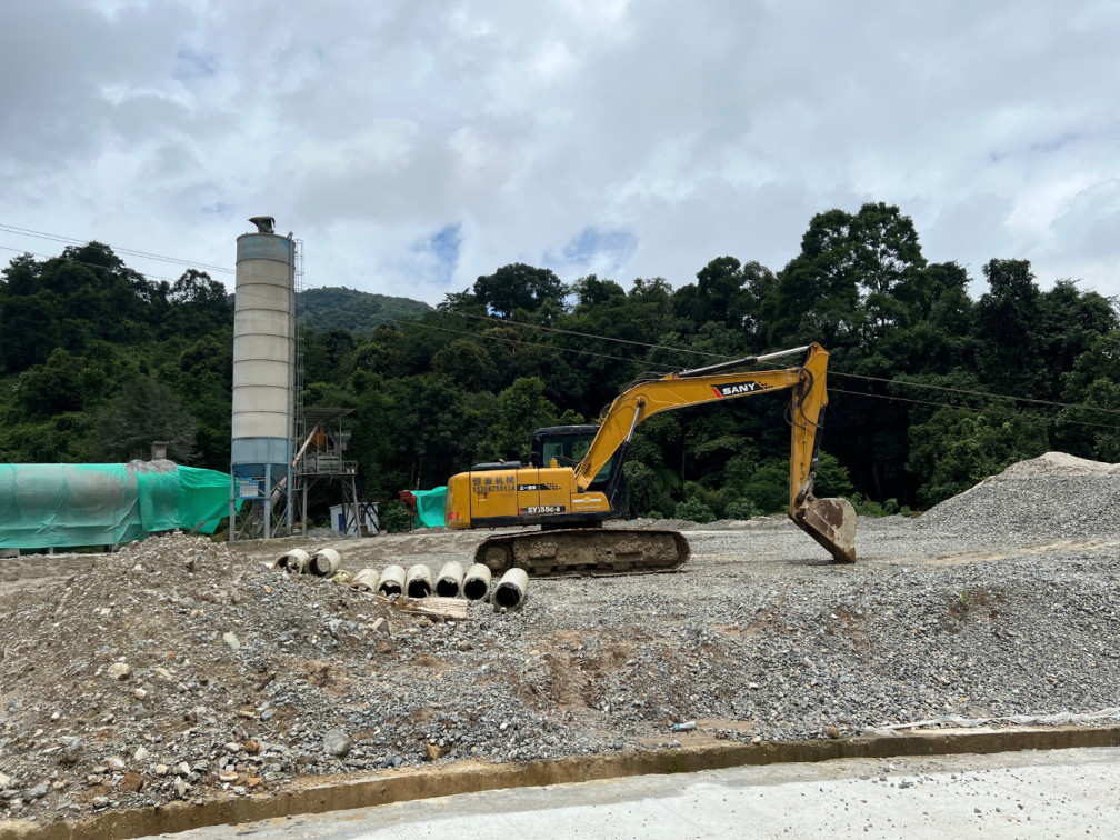 Heavy machinery and concrete towers carving through the green hills
